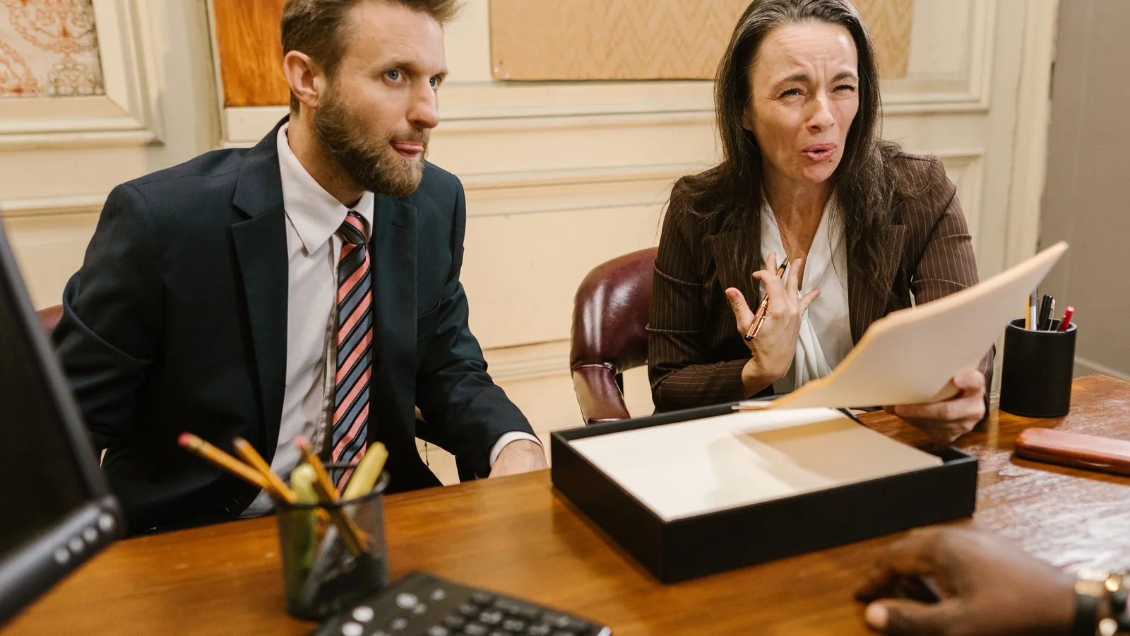 Two legal professionals discuss documents across a conference table in a professional office.