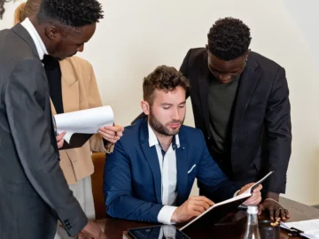 Four professionals review documents together around a conference table in a modern office.