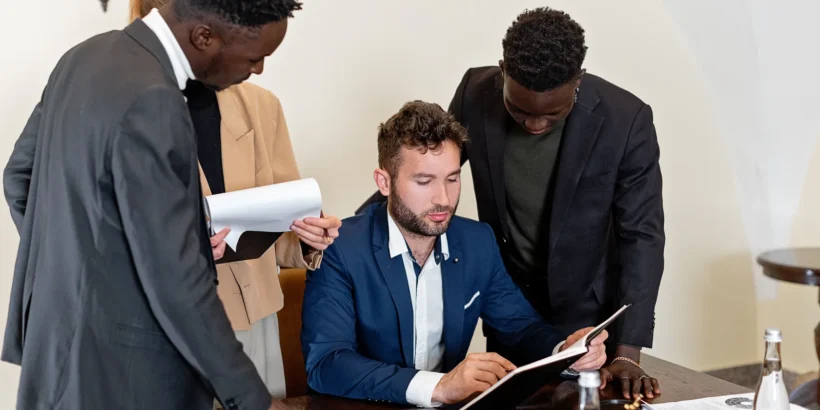 Four professionals review documents together around a conference table in a modern office.