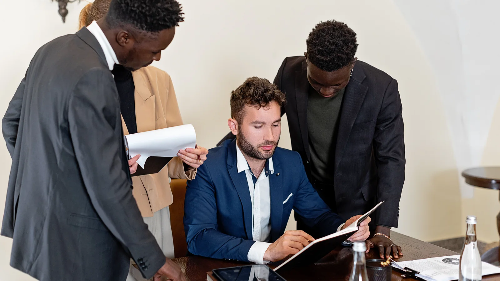 Four professionals review documents together around a conference table in a modern office.