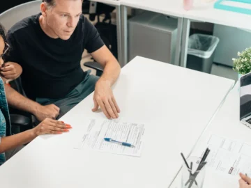 Adults reviewing documents together around a desk in a modern office.