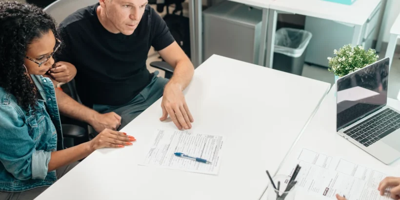 Adults reviewing documents together around a desk in a modern office.