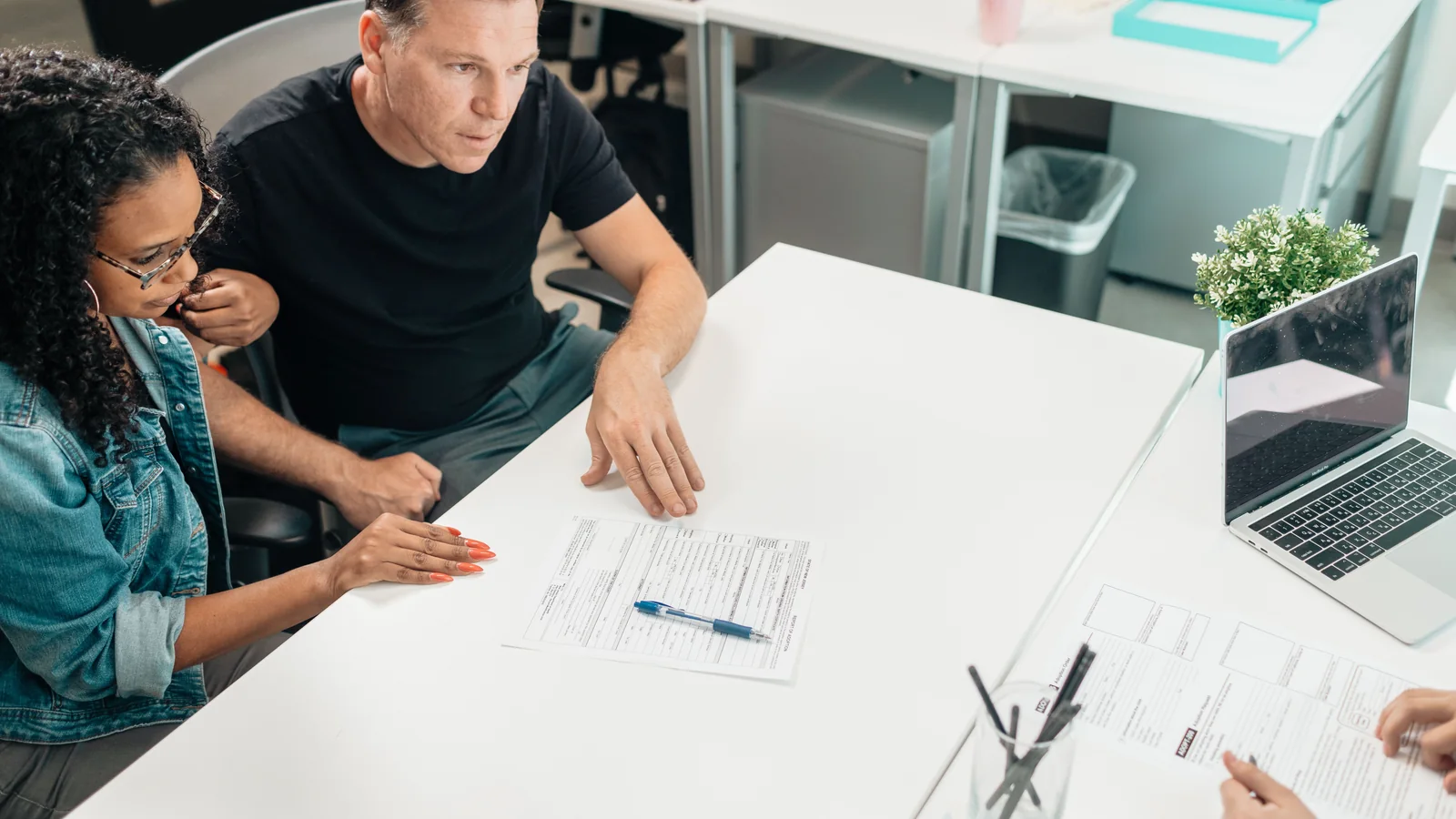 Adults reviewing documents together around a desk in a modern office.