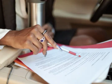 Close-up of a person writing on paperwork inside a vehicle.