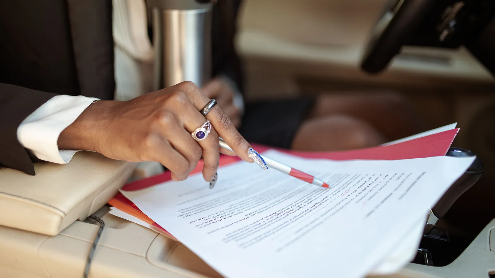 Close-up of a person writing on paperwork inside a vehicle.