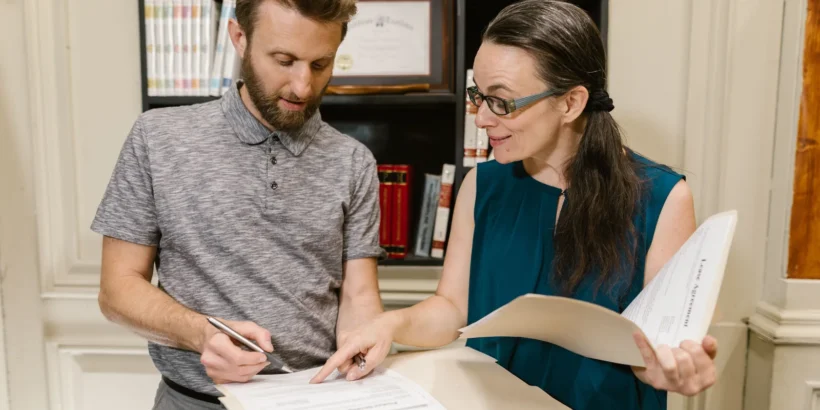 An attorney and a client review paperwork together at a desk in a law office.