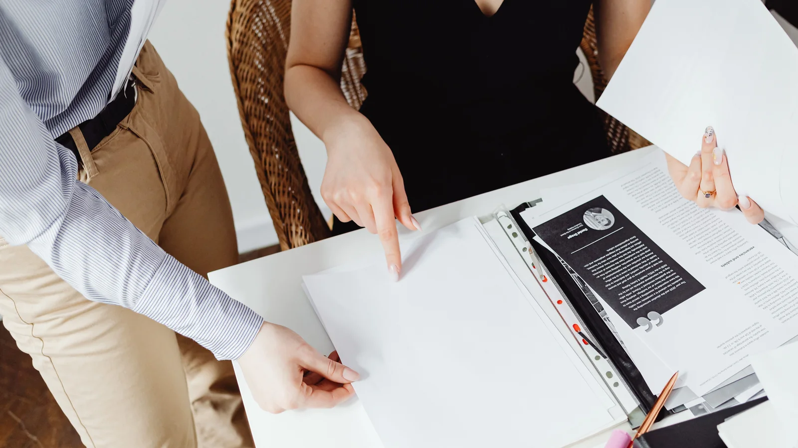 Two people review paperwork together at a table, with one person pointing to a document.