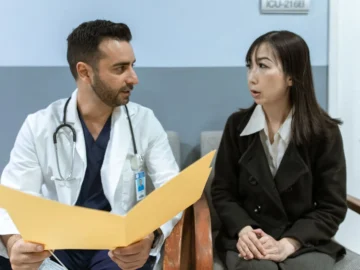 Doctor and patient seated in a clinic reviewing a yellow folder together.
